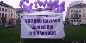 Užrašas plakate: „300 tūkstančių Latvijos gyventojų neturi balso teisės!“ 